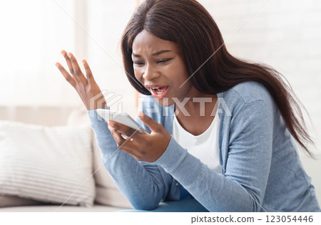 Telephone arguing. Portrait of young black woman shouting at mobile phone at home, copy space Telephone arguing. Portrait of young black woman shouting at mobile phone at home, copy space 123054446