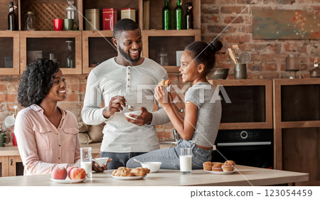 Positive african american family having breakfast in beautiful kitchen, talking while eating, free space 123054459