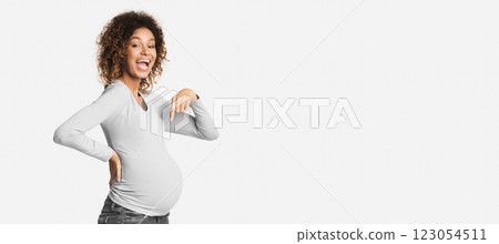 Overjoyed black pregnant woman pointing at her belly over white studio background Overjoyed black pregnant woman pointing at her belly over white studio background 123054511