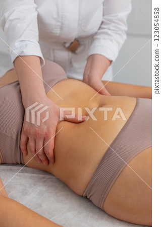 Cosmetologist massagist making woman spa anti-cellulite treatment massage scrubbing belly with scrub 123054858