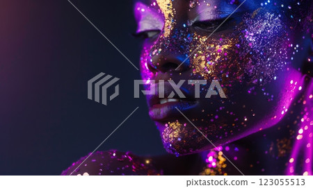 A close-up of a black woman's face covered in purple, gold, and silver glitter. Her face is lit with pink and blue light. 123055513