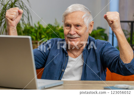 Overjoyed senior man working on laptop celebrate success win money in lottery get online good news 123056032
