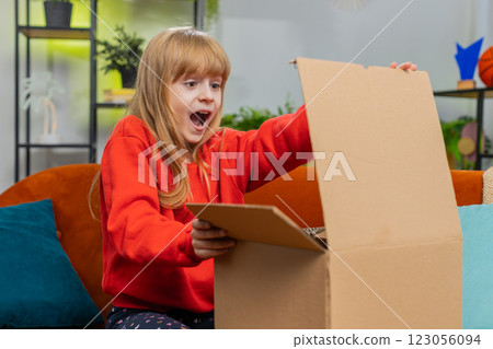 Happy child girl shopper unpacking cardboard box delivery parcel online shopping purchase at home 123056094