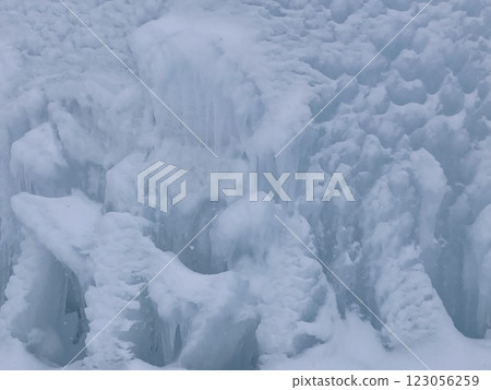 A photo of snow piled up on an uneven ice wall 123056259