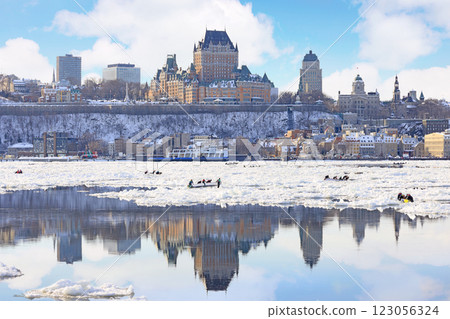 Traditional Ice Canoe Race from Quebec to Levis during winter Carnival with city skyline reflected on the frozen Saint Lawrence River 123056324