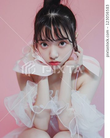 Portrait of an Asian woman in a frilly dress against a pink background 123056583