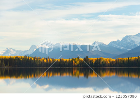 Tranquil lake waters at the mountain foot in autumn forest. 123057090