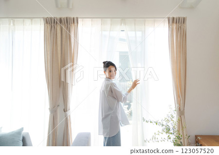 Woman opening curtains in living room 123057520