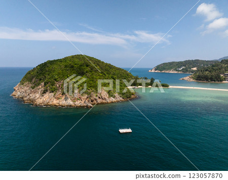 Lush green island surrounded by deep blue ocean and a small sandy beach connecting another shore. Ko Pha Ngan, Thailand. 123057870