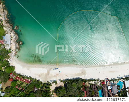A serene aerial view showcasing emerald waters with ripples meeting a white sandy beach surrounded by lush greenery. Haad Rin. Ko Pha Ngan, Thailand. A serene aerial view showcasing emerald waters with ripples meeting a white sandy beach surrounded by lush greenery. Haad Rin. Ko Pha Ngan, Thailand. 123057871