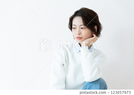 Young woman sitting in front of a wall 123057973