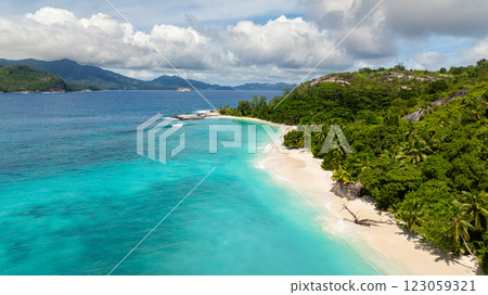A white sandy beach with clear turquoise water, bordered by dense green vegetation. Therese. Seychelles, Mahe. 123059321