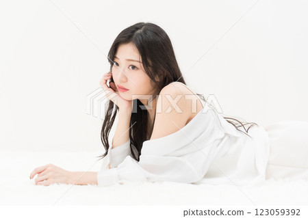 Beauty image: A young woman in a white shirt lying down with her cheek resting on the floor. Ennui 123059392