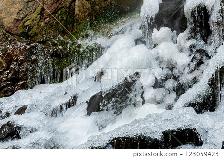 Water flowing over rocks of a frozen waterfall 123059423