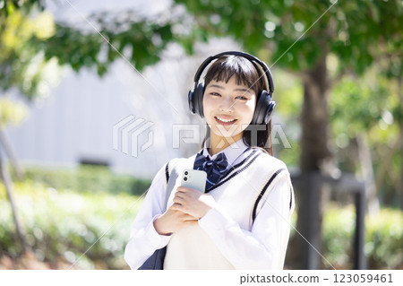A high school girl wearing headphones and holding a smartphone A high school girl wearing headphones and holding a smartphone 123059461