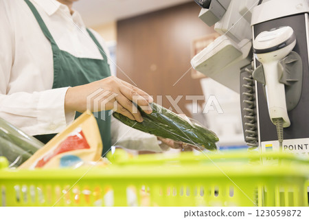 A female employee scanning items at the cash register 123059872