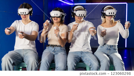 In darkened hall of gaming club, four friends in VR helmet takes part in group game In darkened hall of gaming club, four friends in VR helmet takes part in group game 123060298