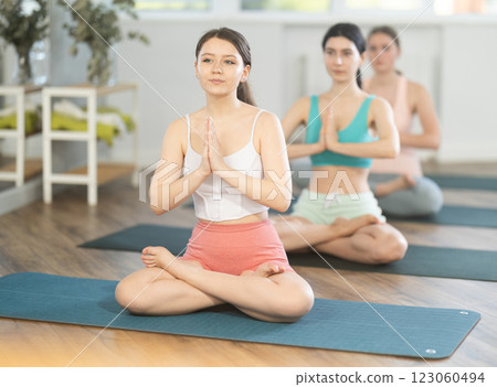 Young girl teaches yoga lesson, shows students technique of performing padmasana asana 123060494