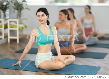 Young girl teaches yoga lesson, shows students technique of performing padmasana asana Young girl teaches yoga lesson, shows students technique of performing padmasana asana 123060527