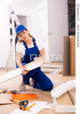 Female builder checking laminate planks before installation Female builder checking laminate planks before installation 123060629