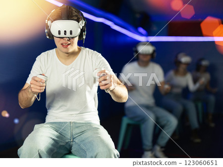 In darkened hall of gaming club, guy in VR helmet takes part in group game In darkened hall of gaming club, guy in VR helmet takes part in group game 123060651