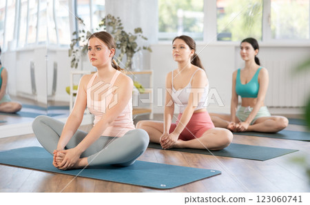 Young girl teaches yoga lesson, shows students technique of performing butterfly pose asana 123060741