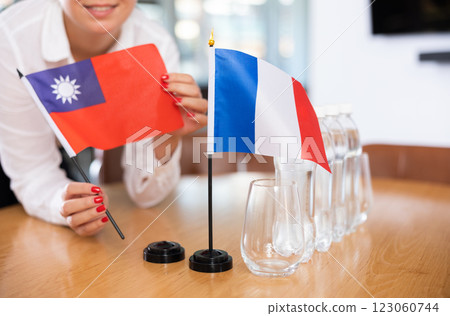 Woman secretary prepares an office for negotiations - she places flags of France and Taiwan table Woman secretary prepares an office for negotiations - she places flags of France and Taiwan table 123060744