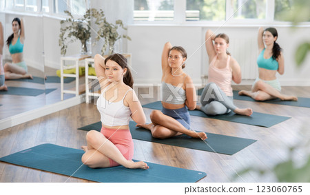 Young girl practicing Cow Face Pose during group yoga session Young girl practicing Cow Face Pose during group yoga session 123060765