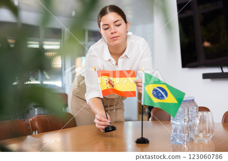 Young female assistant putting up brazilian and spanish flags on table for international negotiations 123060786
