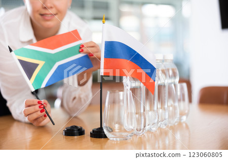 Young woman puts flags of South Africa and Russia on table in office 123060805