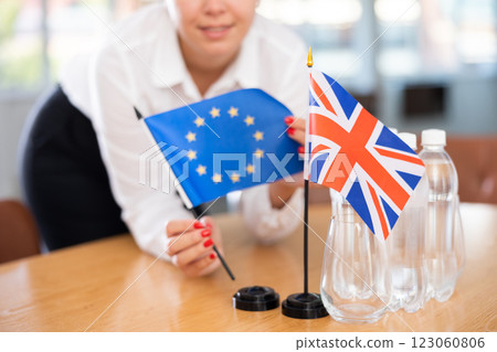 Flags of Council of Europe and Great Britain in female hands preparing meeting room 123060806