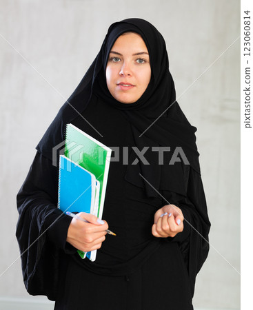 Young student woman dressed in traditional islamic clothes holding notebooks 123060814