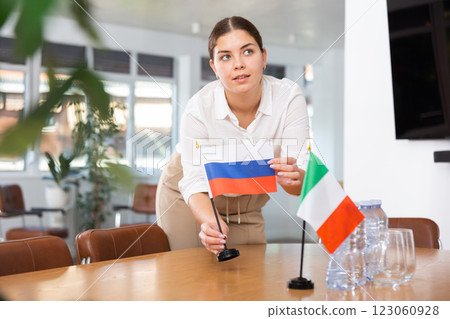 Young woman puts flags of Russia and Italy on table 123060928