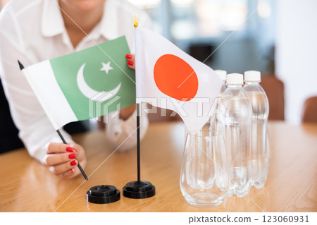 Flags of Pakistan and Japan in female hands in meeting room 123060931