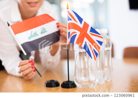 Little flag of Great Britain on table and flag of Iraq put next to it by young woman 123060961
