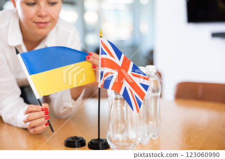 Flags of Ukraine and United Kingdom in female hands on negotiating table 123060990