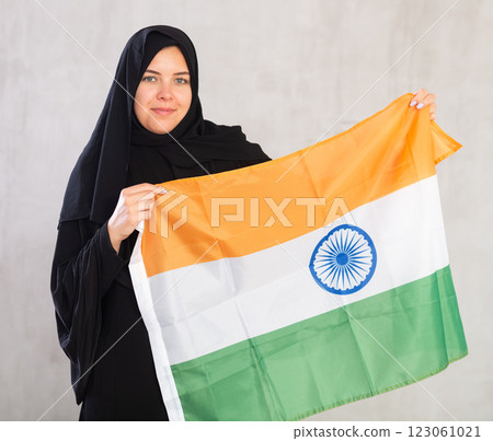 Happy young woman dressed in traditional islamic clothes with indian flag 123061021