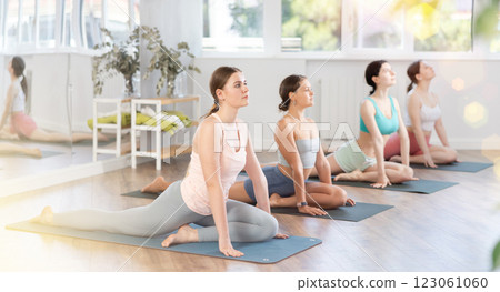 Young girl teaches yoga lesson, shows students technique of performing kapotasana asana 123061060