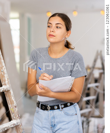 Woman with documents in her hands checks the quality of the completed repairs in cottage room 123061061
