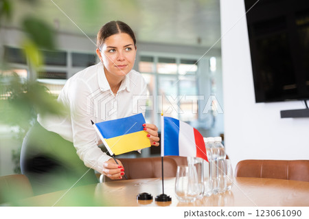 Woman secretary prepares an office for negotiations - she places flags of France and Ukrain table 123061090