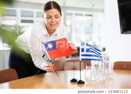 Employee of delegation prepares negotiating table - sets up flag of Greece and Taiwan 123061112