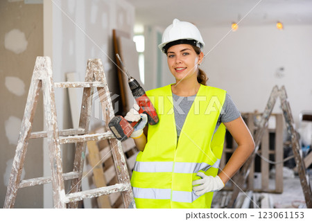 Female foreman in protective yellow vest and hard hat with screwdriver in hand 123061153