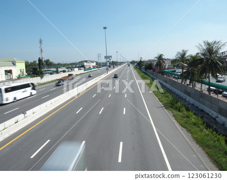 A clear highway scene with vehicles and palm trees under blue sky 123061230