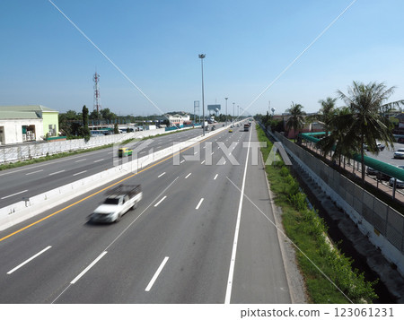 A clear highway scene with vehicles, palm trees, and buildings nearby 123061231