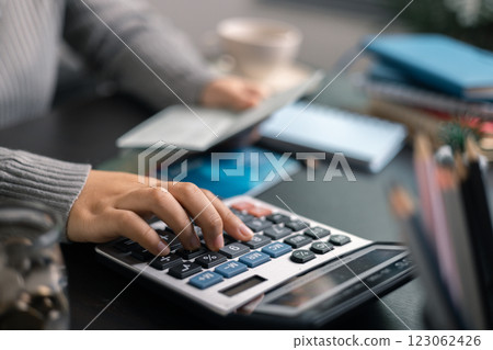Finance bank tax expense accounting budget money businessman hand use calculator Financial calculate accountant close up calculator with graph chart write office desk Business expense analysis saving 123062426