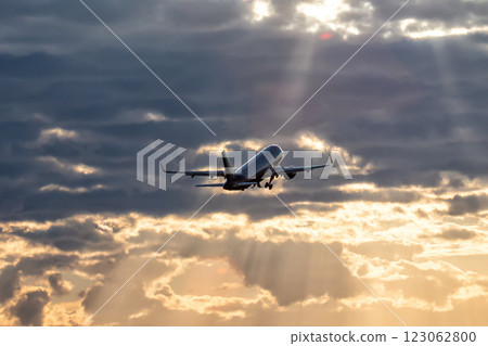 A modern passenger airliner takes off into the dawn sky towards the rays of the sun A modern passenger airliner takes off into the dawn sky towards the rays of the sun 123062800