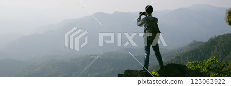 Man traveler with backpack hiking outdoor travel lifestyle and adventure concept. join of tourist for green mountain tour beauty of nature and expansive sky people of tourism. banner with copy space Man traveler with backpack hiking outdoor travel lifestyle and adventure concept. join of tourist for green mountain tour beauty of nature and expansive sky people of tourism. banner with copy space 123063922