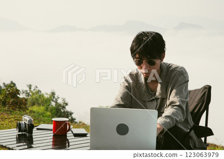 Young business man working computer on peak hill. Hiker online shopping on laptop at sunset, sunrise on top mountain, freelance person remote work with digital tablet. travel vacation holiday concept 123063979