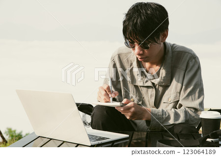 Young business man working computer on peak hill. Hiker online shopping on laptop at sunset, sunrise on top mountain, freelance person remote work with digital tablet. travel vacation holiday concept 123064189