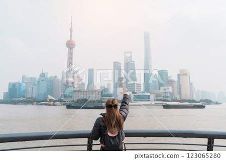 woman traveler visiting in Shanghai, China. Female Tourist with backpack sightseeing Shanghai view of Lujiazui in The Bund of Shanghai. landmark and popular for tourism attractions. Vacation concept 123065280